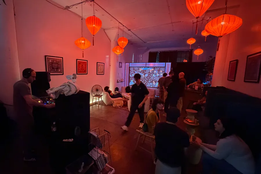 Bu Tea Den interior — lounge seating, red lanterns, and projection wall
