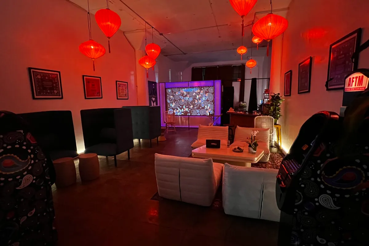 Bu Tea Den event space — red lanterns, lounge seating, Paisley ID projection wall